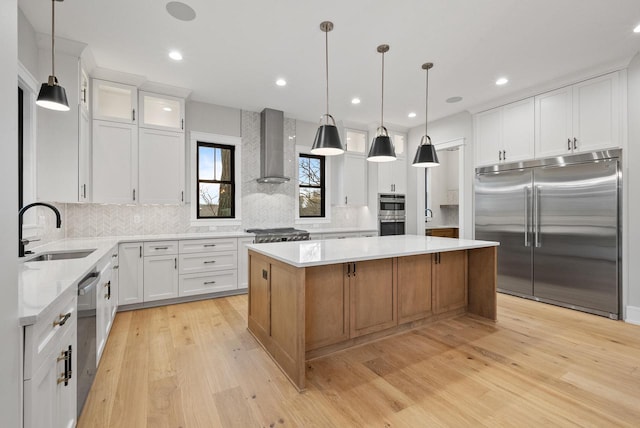 N1931 Linn Rd, Lake Geneva, WI 53147 - kitchen with wall chimney range hood, appliances with stainless steel finishes, a center island, a sink, and light wood-style flooring