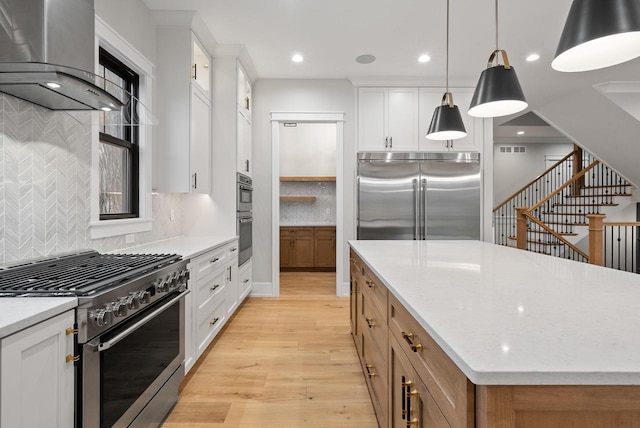 N1931 Linn Rd, Lake Geneva, WI 53147 - kitchen with visible vents, a kitchen island, wall chimney range hood, high quality appliances, and light wood-type flooring
