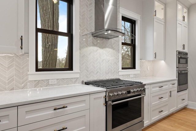 N1931 Linn Rd, Lake Geneva, WI 53147 - kitchen featuring glass insert cabinets, wall chimney range hood, white cabinets, tasteful backsplash, and appliances with stainless steel finishes
