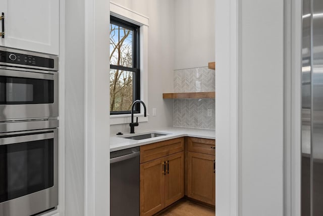 N1931 Linn Rd, Lake Geneva, WI 53147 - kitchen featuring decorative backsplash, brown cabinetry, a sink, light countertops, and stainless steel appliances