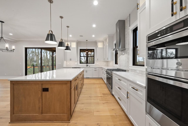 N1931 Linn Rd, Lake Geneva, WI 53147 - kitchen featuring wall chimney range hood, a center island, light countertops, backsplash, and stainless steel appliances