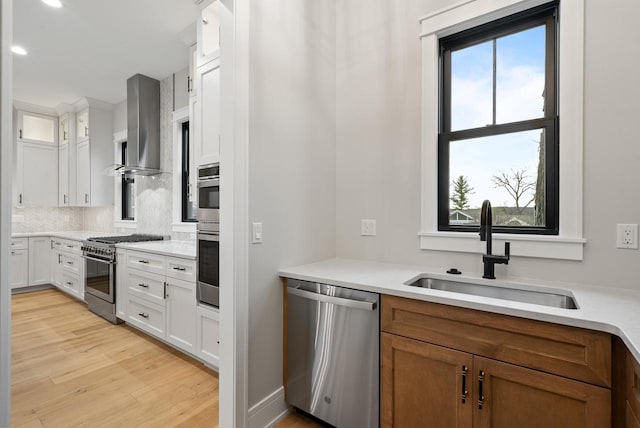 N1931 Linn Rd, Lake Geneva, WI 53147 - kitchen with wall chimney range hood, appliances with stainless steel finishes, a sink, light wood-style floors, and white cabinetry