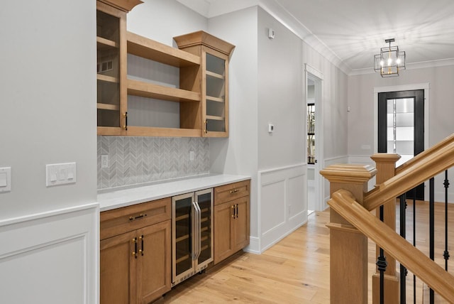 N1931 Linn Rd, Lake Geneva, WI 53147 - bar featuring a notable chandelier, light wood-style floors, beverage cooler, decorative backsplash, and ornamental molding