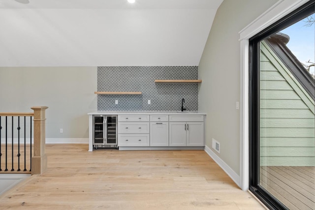 N1931 Linn Rd, Lake Geneva, WI 53147 - bar featuring light wood finished floors, wet bar, lofted ceiling, wine cooler, and backsplash