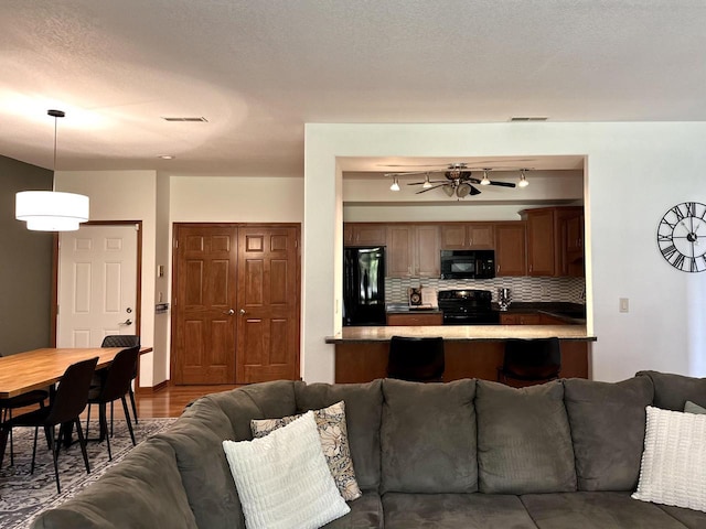 living area with ceiling fan and visible vents