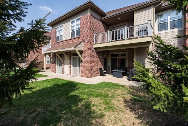back of property featuring a lawn, a patio area, brick siding, and a balcony