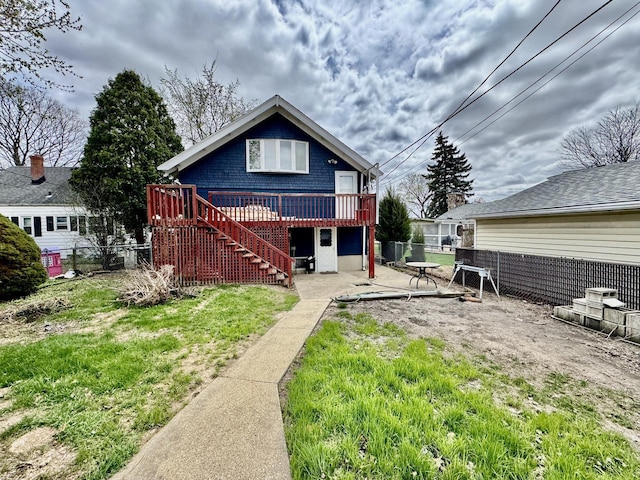 rear view of house with a fenced backyard, a deck, a lawn, and stairway