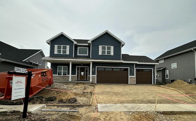 craftsman house featuring a porch, a standing seam roof, driveway, stone siding, and board and batten siding