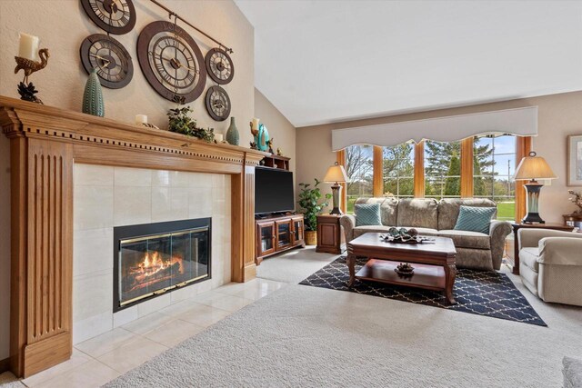 living area featuring a tiled fireplace, light tile patterned floors, light colored carpet, and vaulted ceiling