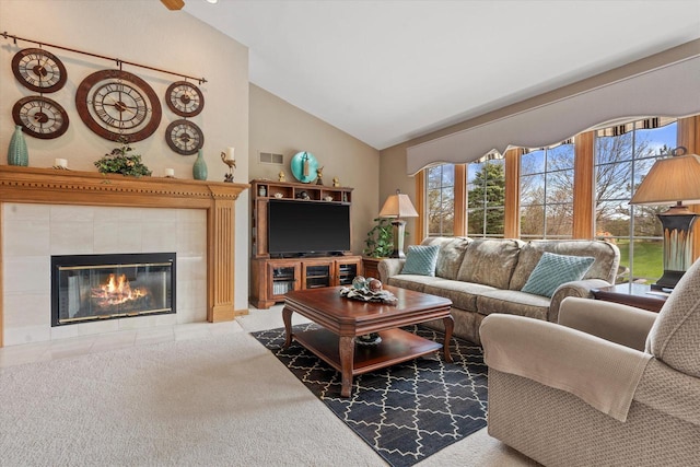 living area featuring visible vents, a tiled fireplace, and high vaulted ceiling