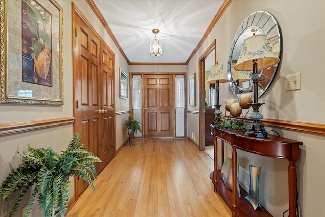 entryway featuring light wood-type flooring, crown molding, and a notable chandelier