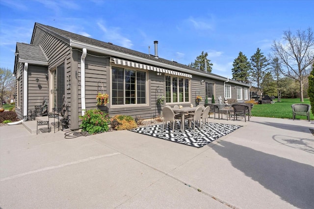 rear view of house with a patio, outdoor dining space, and a yard