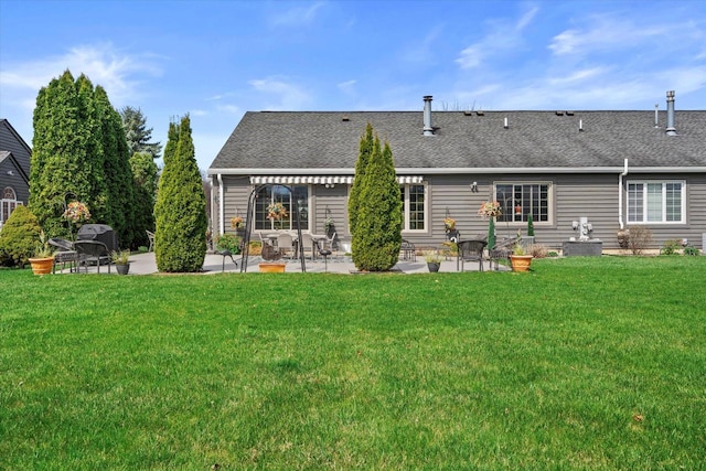 back of property featuring a lawn, a shingled roof, and a patio area