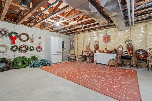 unfinished basement featuring freestanding refrigerator and brick wall