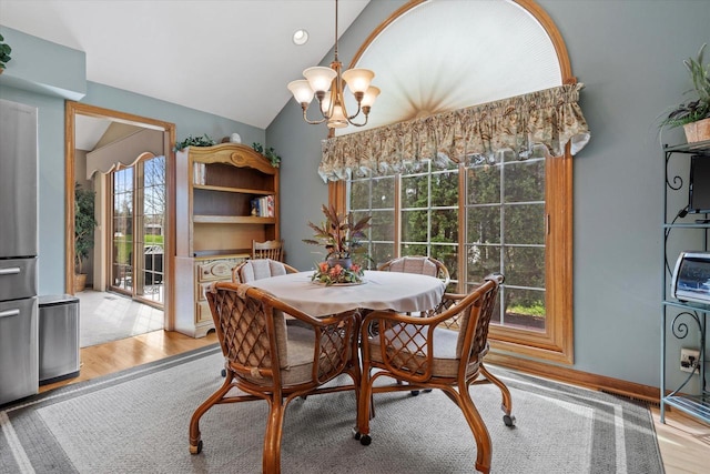 dining space with a chandelier, light wood-style flooring, and lofted ceiling