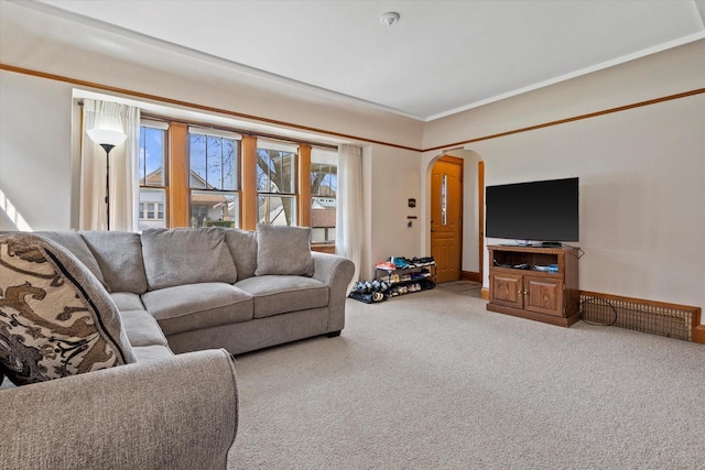 carpeted living room with baseboards, ornamental molding, and arched walkways