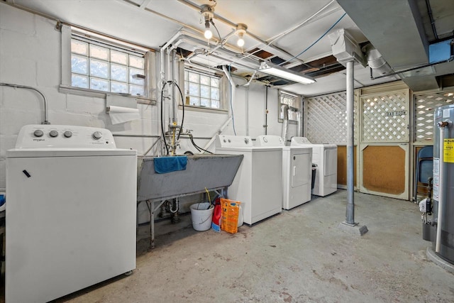 clothes washing area featuring concrete block wall, water heater, laundry area, and washer and clothes dryer