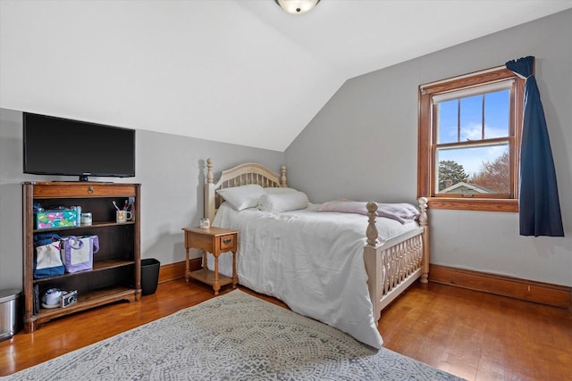 bedroom with baseboards, wood finished floors, and vaulted ceiling