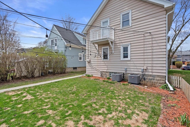 back of property featuring cooling unit, a lawn, fence, and a balcony