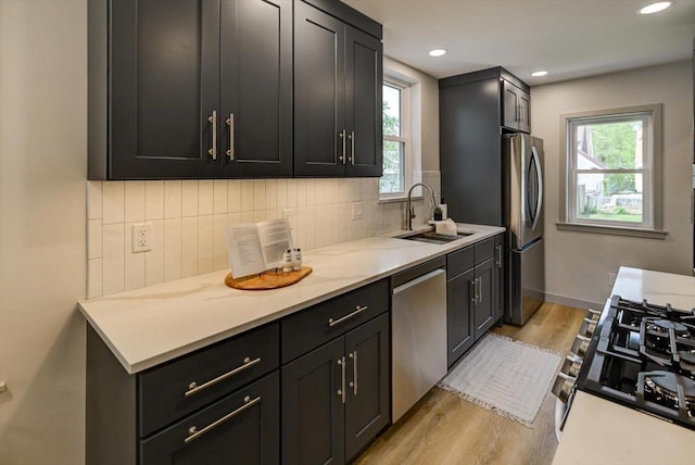 14 Wirth Ct, Madison, WI 53704 - kitchen featuring stainless steel appliances, a sink, light wood-style flooring, decorative backsplash, and dark cabinetry