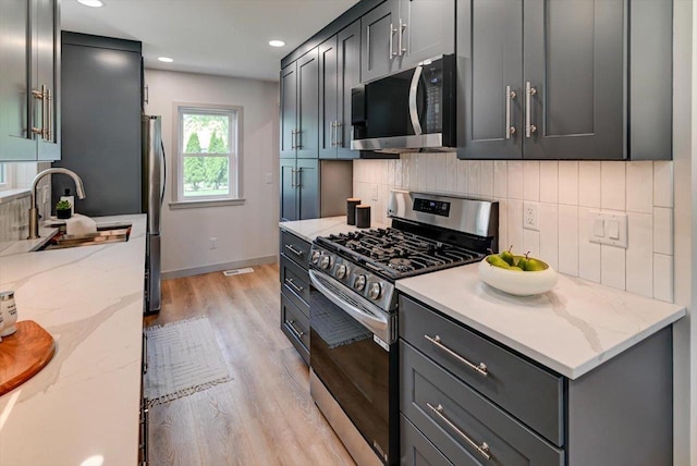 14 Wirth Ct, Madison, WI 53704 - kitchen with appliances with stainless steel finishes, light wood finished floors, tasteful backsplash, light stone countertops, and a sink