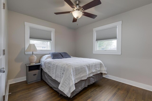 bedroom with baseboards, multiple windows, a ceiling fan, and dark wood-style flooring