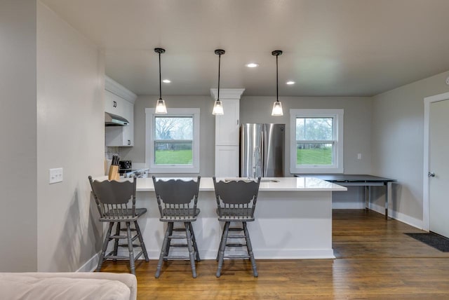 kitchen with a peninsula, dark wood-type flooring, light countertops, white cabinets, and stainless steel appliances