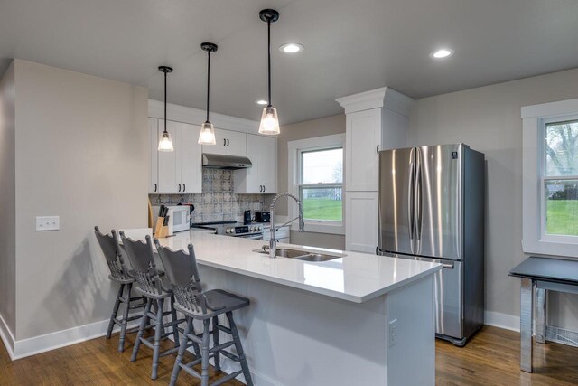 kitchen with a peninsula, baseboards, tasteful backsplash, a sink, and stainless steel appliances