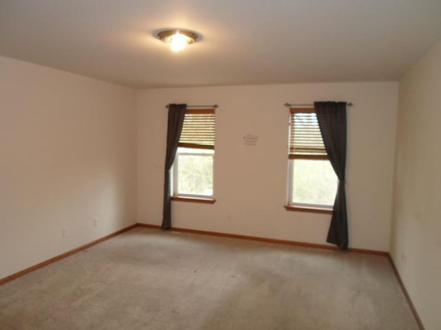 unfurnished room with baseboards and light carpet