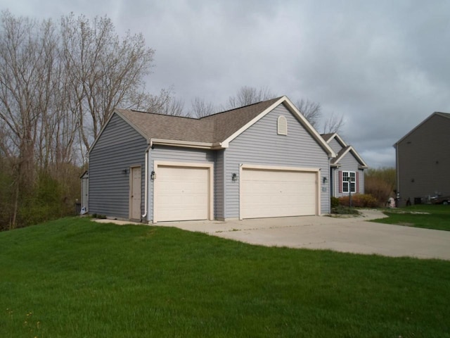 exterior space featuring a garage, roof with shingles, a front yard, and concrete driveway