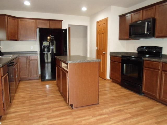 kitchen with a center island, light wood-style flooring, black appliances, and dark countertops