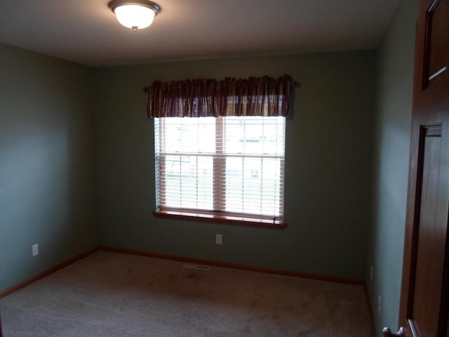 spare room featuring carpet flooring and baseboards