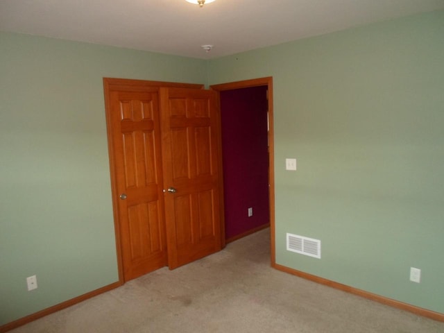 unfurnished bedroom featuring baseboards, visible vents, light carpet, and a closet