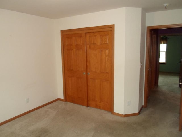 unfurnished bedroom featuring carpet floors, baseboards, and a closet