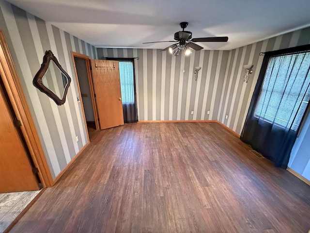 interior space with baseboards, wallpapered walls, ceiling fan, and wood finished floors