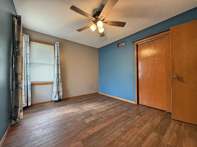 unfurnished bedroom with a ceiling fan, baseboards, wood finished floors, visible vents, and a closet