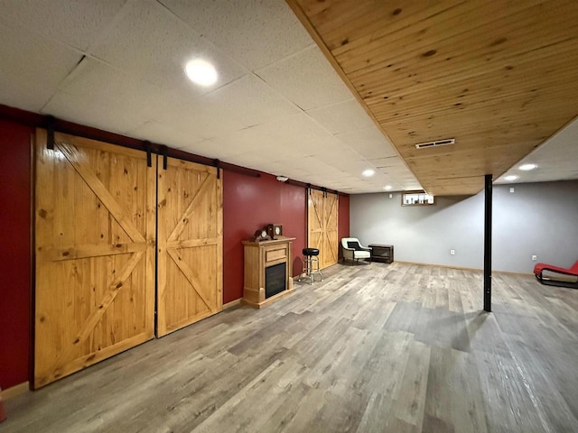 finished below grade area featuring visible vents, recessed lighting, wood finished floors, and a fireplace