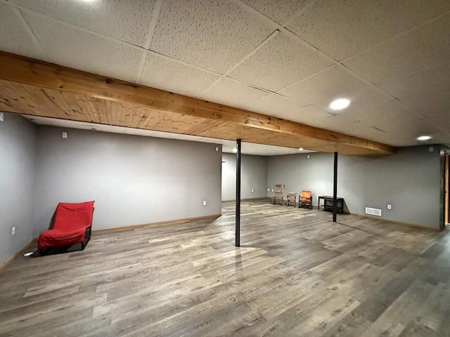 finished basement with baseboards, visible vents, and wood finished floors