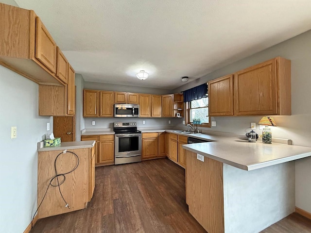 kitchen with a sink, light countertops, dark wood finished floors, stainless steel appliances, and a peninsula
