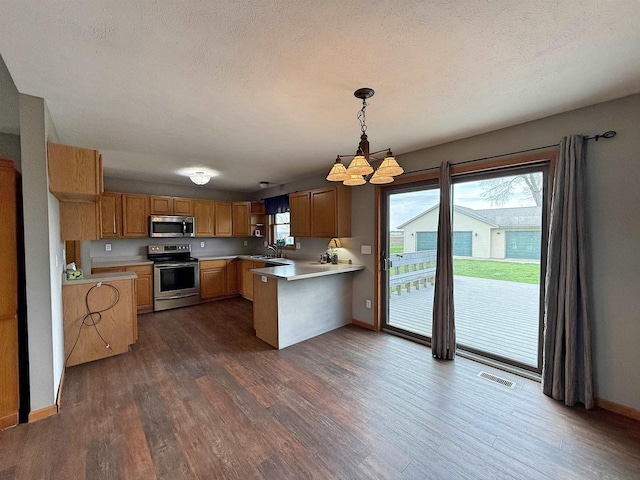 kitchen featuring light countertops, dark wood finished floors, appliances with stainless steel finishes, and a chandelier