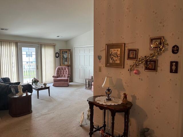 living room featuring carpet floors, lofted ceiling, and visible vents