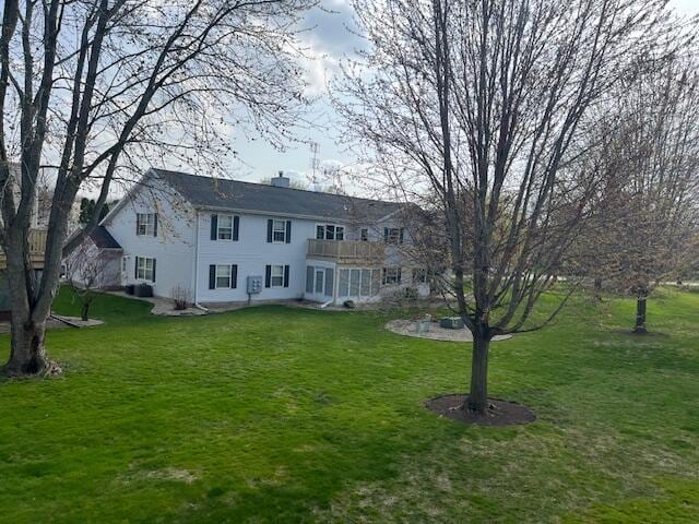 view of front facade featuring a chimney, a balcony, and a front yard