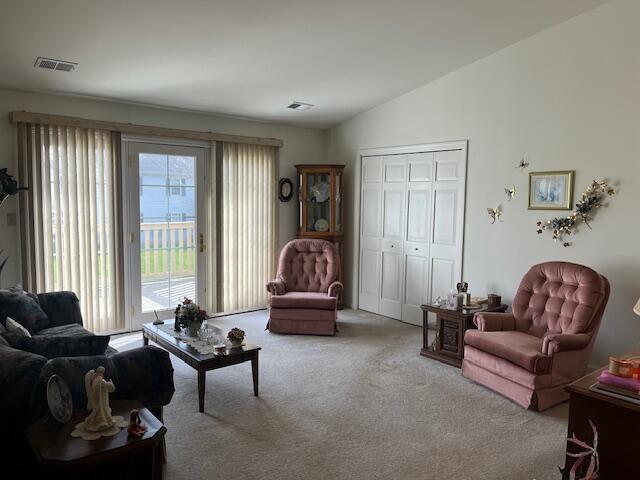 living room featuring carpet flooring, visible vents, and vaulted ceiling