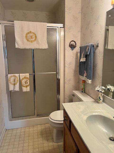 bathroom featuring tile patterned floors, a shower stall, toilet, and wallpapered walls