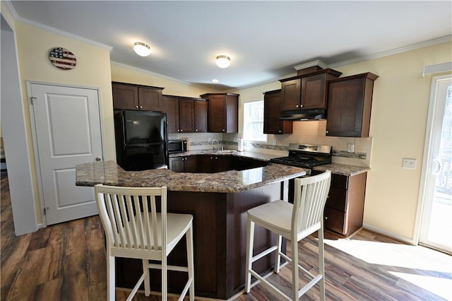 13585 Oswald Rd, Drummond, WI 54832 - kitchen with decorative backsplash, dark brown cabinets, a sink, freestanding refrigerator, and under cabinet range hood