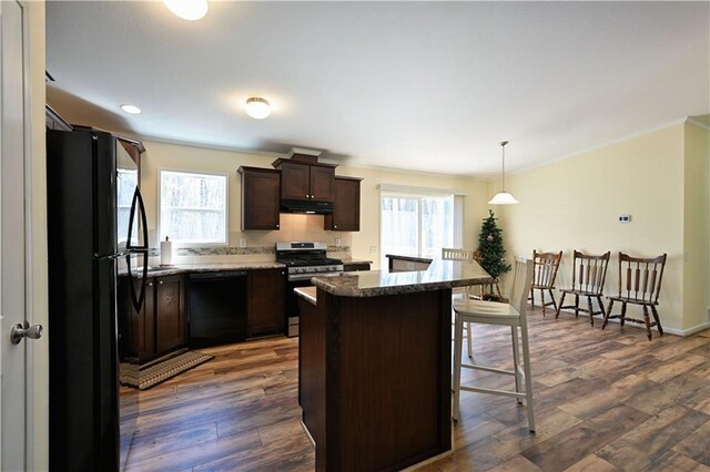 13585 Oswald Rd, Drummond, WI 54832 - kitchen featuring a kitchen breakfast bar, dark brown cabinetry, black appliances, dark wood-style floors, and under cabinet range hood