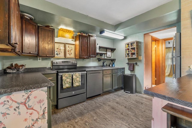 kitchen featuring dark countertops, open shelves, a sink, stainless steel appliances, and dark wood-style floors