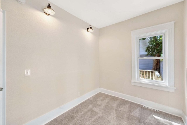 carpeted spare room with visible vents and baseboards