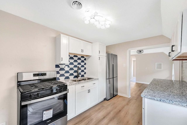 kitchen with a sink, tasteful backsplash, stainless steel appliances, and white cabinets