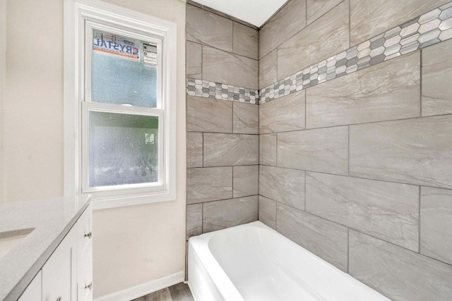 bathroom featuring a bathtub, a shower, wood finished floors, baseboards, and vanity